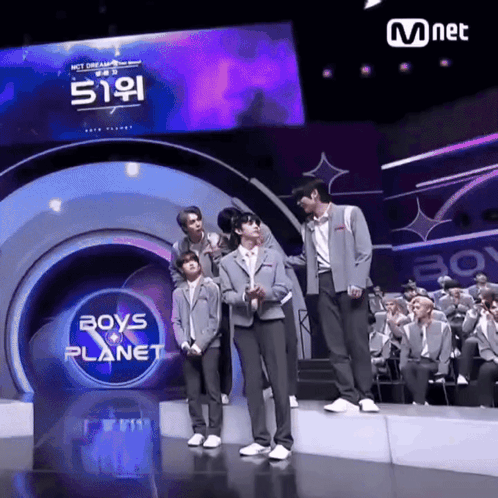 Boys Standing on Stage in Front of Boys Planet Sign