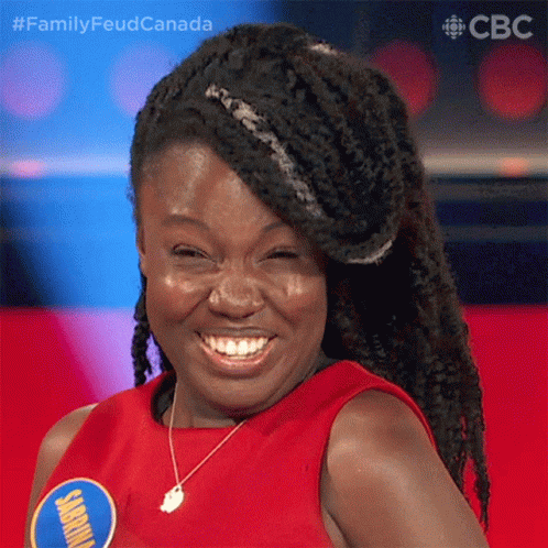 Braided Woman Smiling in Red Shirt With Jamaica Badge