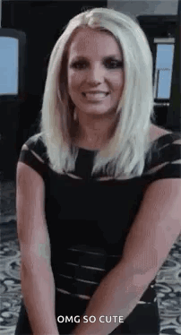 Britney Spears Is Wearing A Black Dress And Smiling While Standing With Her Hands Behind Her Back . GIF