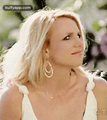 Britney Spears Is Wearing A White Dress And Earrings And Looking At The Camera . GIF