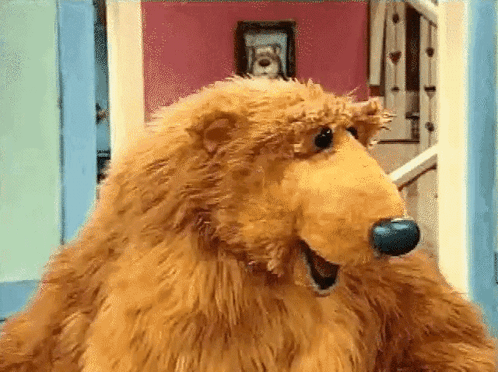 Brown Teddy Bear With Blue Nose Standing in Front of Door