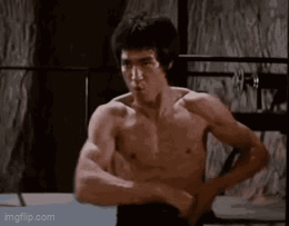 Bruce Lee Flexing Muscles In Boxing Ring GIF