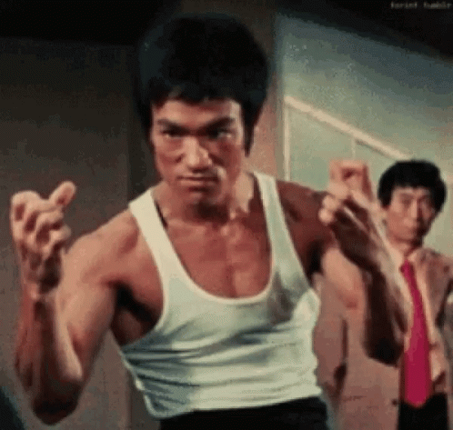 Bruce Lee Is Wearing A White Tank Top And Red Tie . GIF