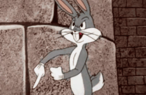 Bugs Bunny Is Standing In Front Of A Brick Wall Pointing GIF