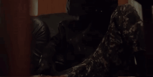 Camouflage Man Sitting at Table With Gun