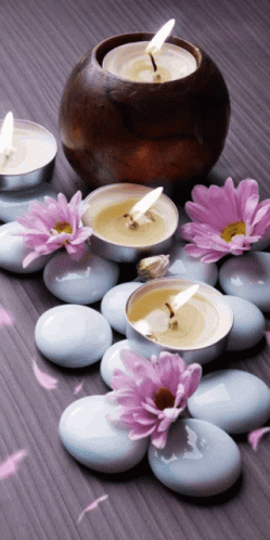Candles And Flowers On Table With Falling Rocks And Petals GIF