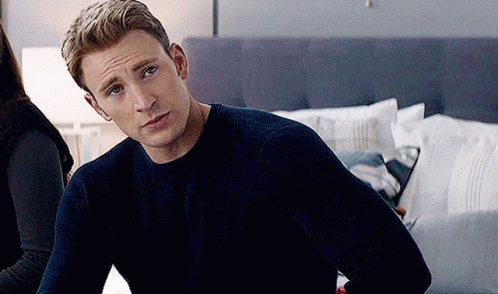 Captain America Is Wearing A Blue Sweater And Sitting On A Bed . GIF