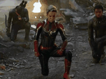 Captain Marvel Is Kneeling Down In Front Of A Group Of Men In Avengers : Age Of Ultron . GIF