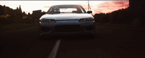 Car Driving Down Road at Sunset
