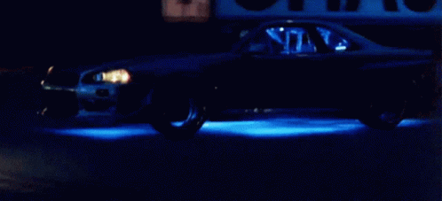 Car Driving Down Street at Night With Blue Lights
