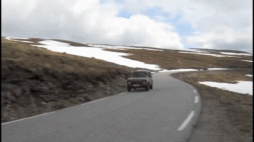 Car Driving on Road with Snowy Hills