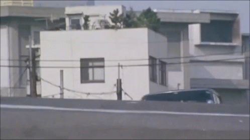Car Parked By White Building With Rooftop Garden GIF