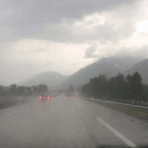 cars are driving down a highway in the rain