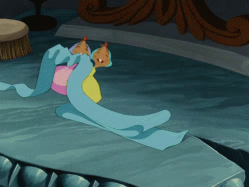 Cartoon Character Laying On Table With Blue Blanket GIF