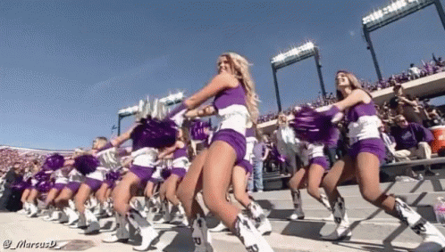 Cheerleaders In Purple And White Uniforms Are Dancing In A Line GIF