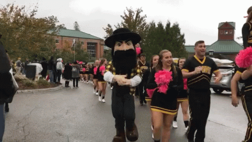 Cheerleaders Marching With Mascot In Black Hat GIF