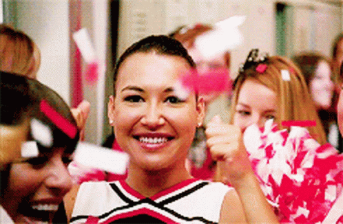 Cheerleaders Smiling With Pom Poms in Locker Room