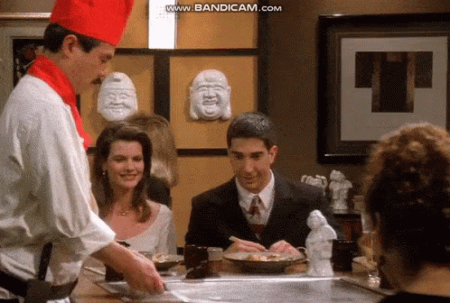 Chef-Hatted Man Cooking for Woman and Suited Man