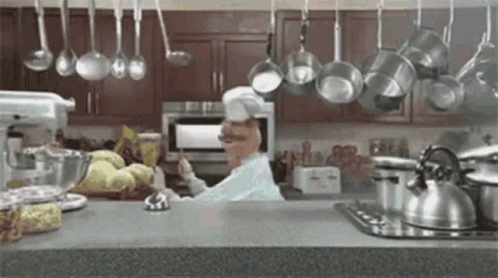 Chef in Kitchen With Hanging Pots and Pans