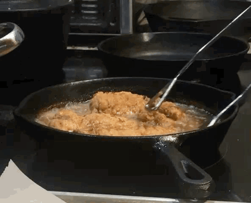 Chicken Is Being Cooked In A Frying Pan On A Stove GIF
