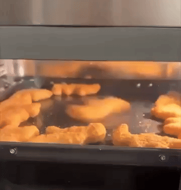Chicken Nuggets Are Being Cooked In A Stainless Steel Oven GIF