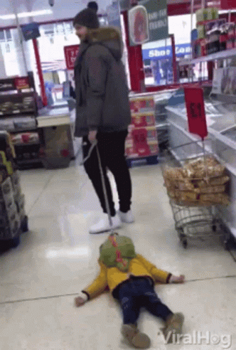 Child Laying On Store Floor With Man Standing Behind GIF
