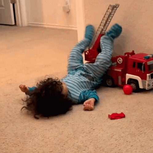 Child Lying Next to Toy Fire Truck