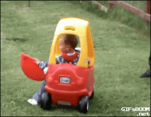 Child Sitting in Red and Yellow Toy Car