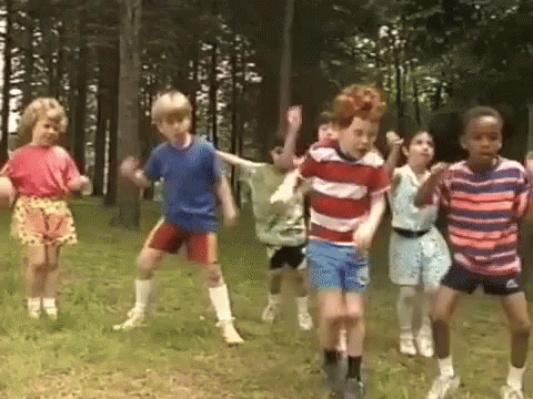 Children Dancing In Grass Near Trees GIF