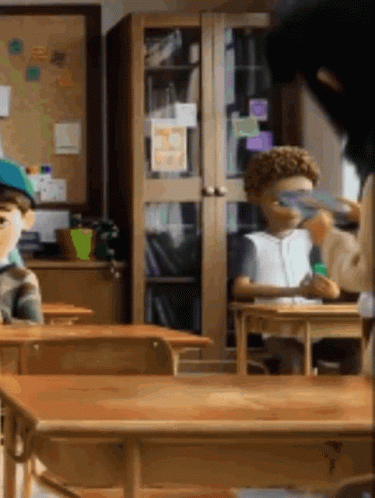 Children Sitting at Desks in Classroom With Bulletin Board