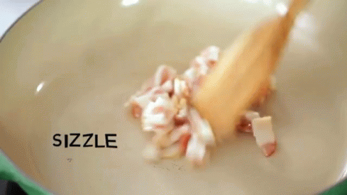 Chopped Bacon Is Being Stirred In A Pan With The Words Sizzle And Sizzle Written On The Bottom GIF