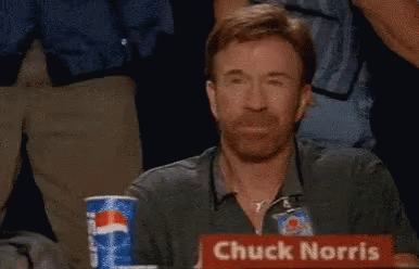 Chuck Norris Is Sitting At A Table With A Sign That Says Chuck Norris GIF