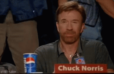 Chuck Norris Is Sitting At A Table With His Fist Up GIF