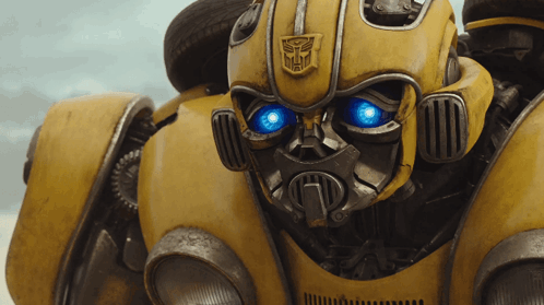 Close Up Yellow Robot With Blue Eyes and Transformer Logo