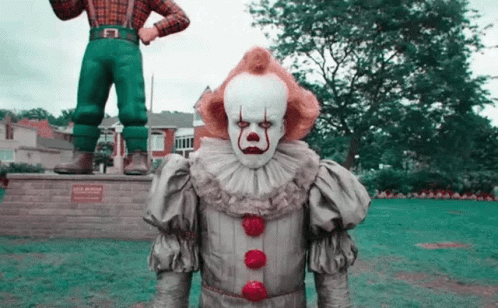 Clown in Front of Statue of Man in Plaid Shirt
