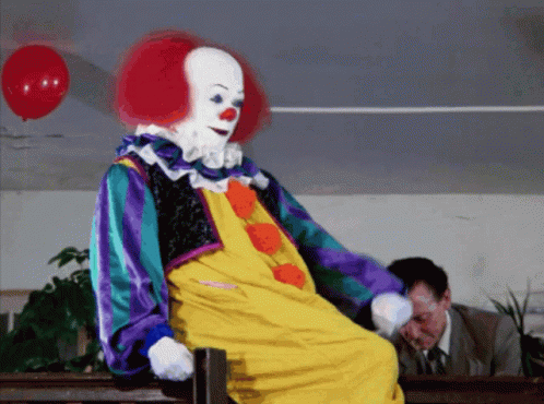 Clown Sitting on Bench With Red Balloon
