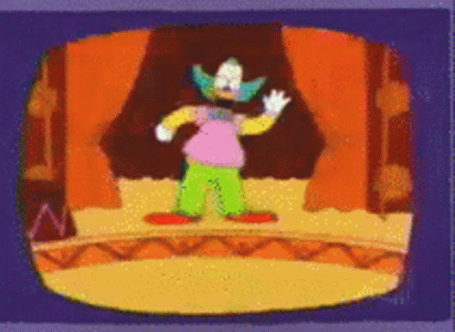 Clown Standing On Stage In Front Of Orange Curtain GIF