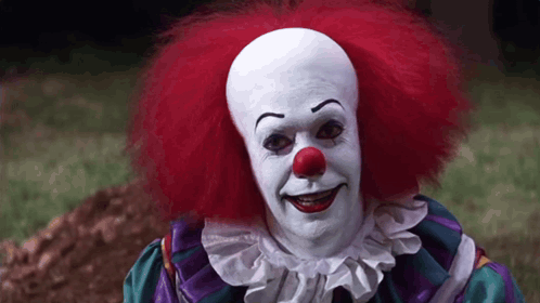 Clown With Red Hair and Red Nose Standing in Grass