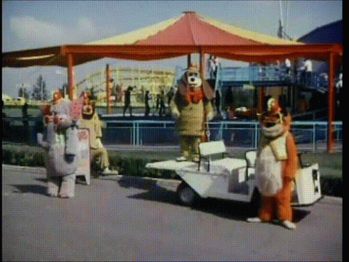 Clowns Standing in Front of Carousel and Small Car