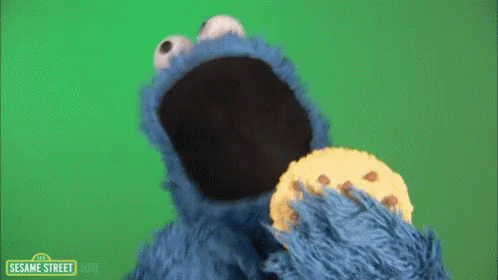Cookie Monster From Sesame Street Eating A Cookie On A Green Background GIF