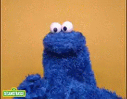 Cookie Monster From Sesame Street Is Standing In Front Of A Yellow Wall . GIF