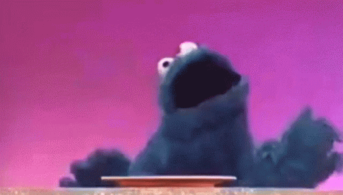 Cookie Monster Sitting on Table Looking at Plate