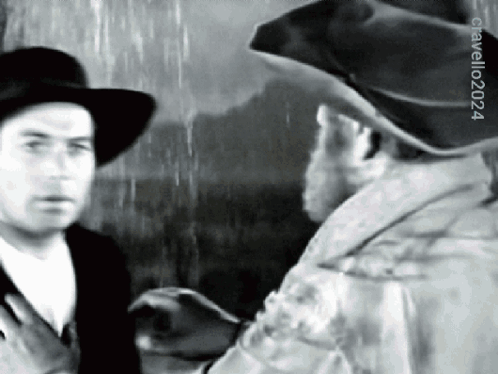 Cowboy Hat Man Talking To Another Man In Black And White GIF