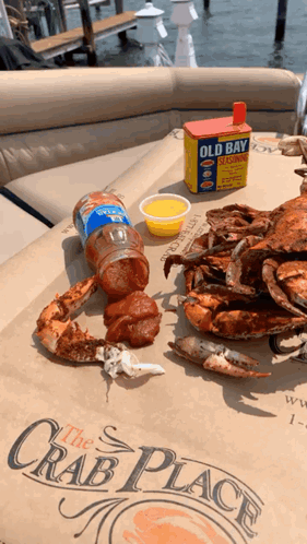 Crabs Are Sitting On A Table With A Box Of Old Bay Seasoning In The Background GIF