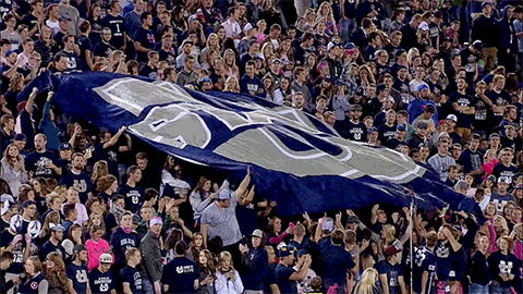 Crowd Holding Blue and White Flag With Letter U