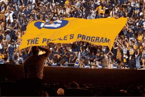 Crowd Holding Yellow Banner Saying The Peace Program