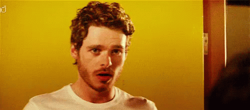 Curly Bearded Man In White Shirt Before Yellow Wall GIF