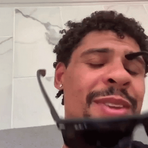 Curly Haired Bearded Man Brushing Eyebrows With Sunglasses