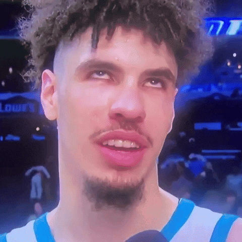 Curly-Haired Bearded Man In Blue-White Jersey On Mic GIF