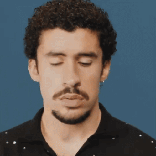 Curly-Haired, Bearded Man Making Funny Face Eyes Closed